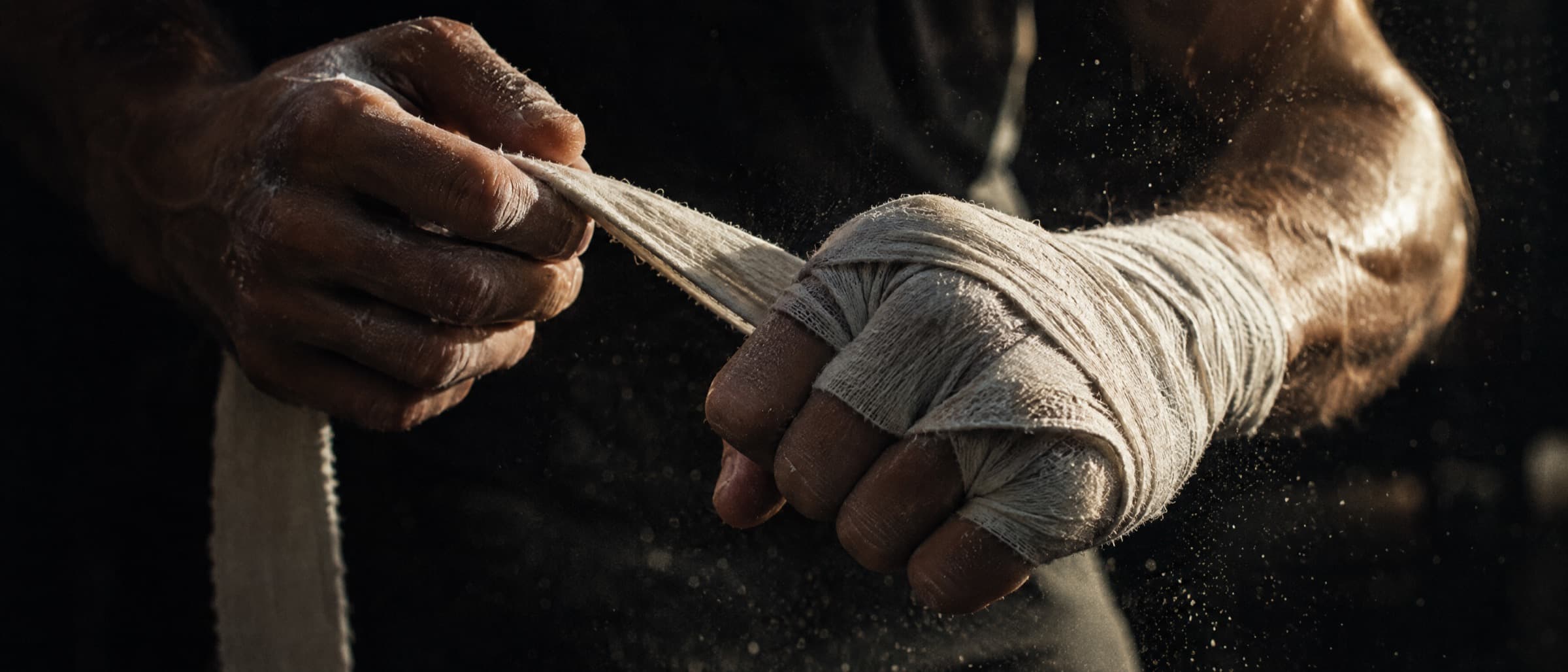 A fighter wraps their hands in warm side light